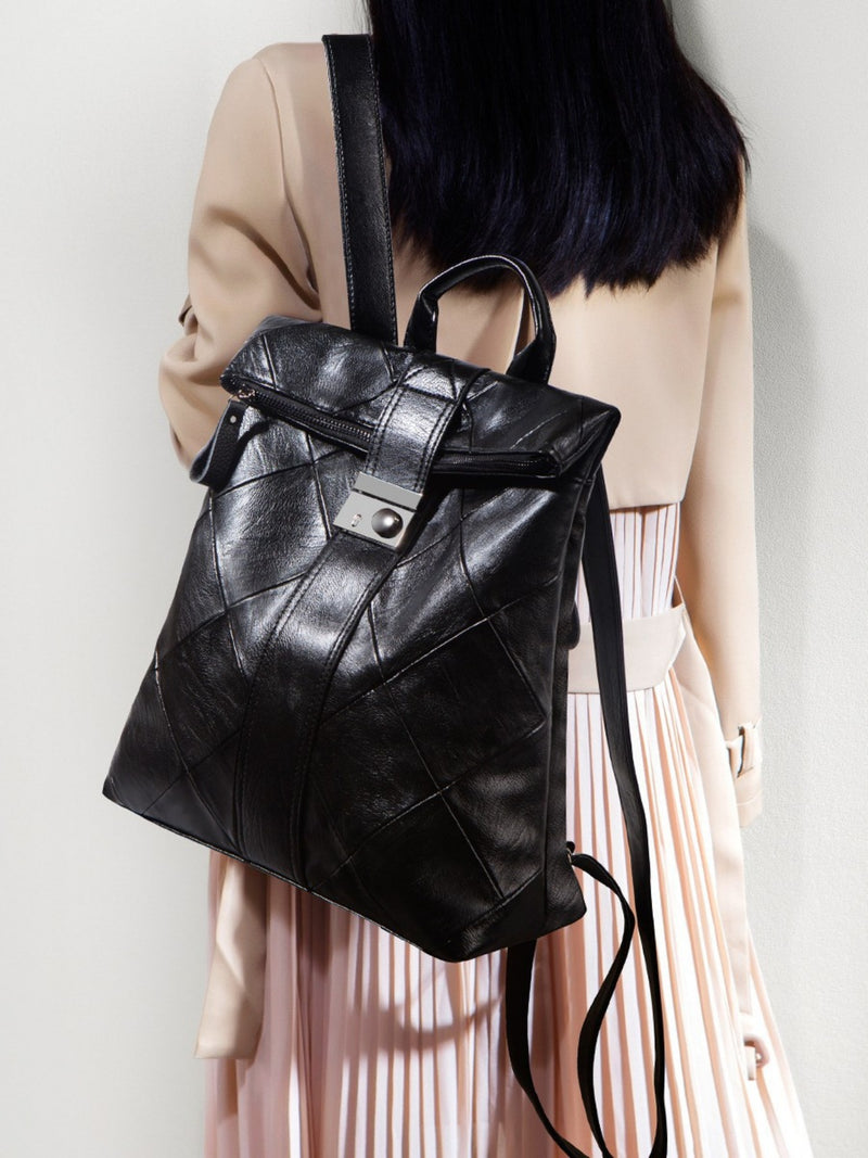 Black leather backpack worn by a person against a neutral background