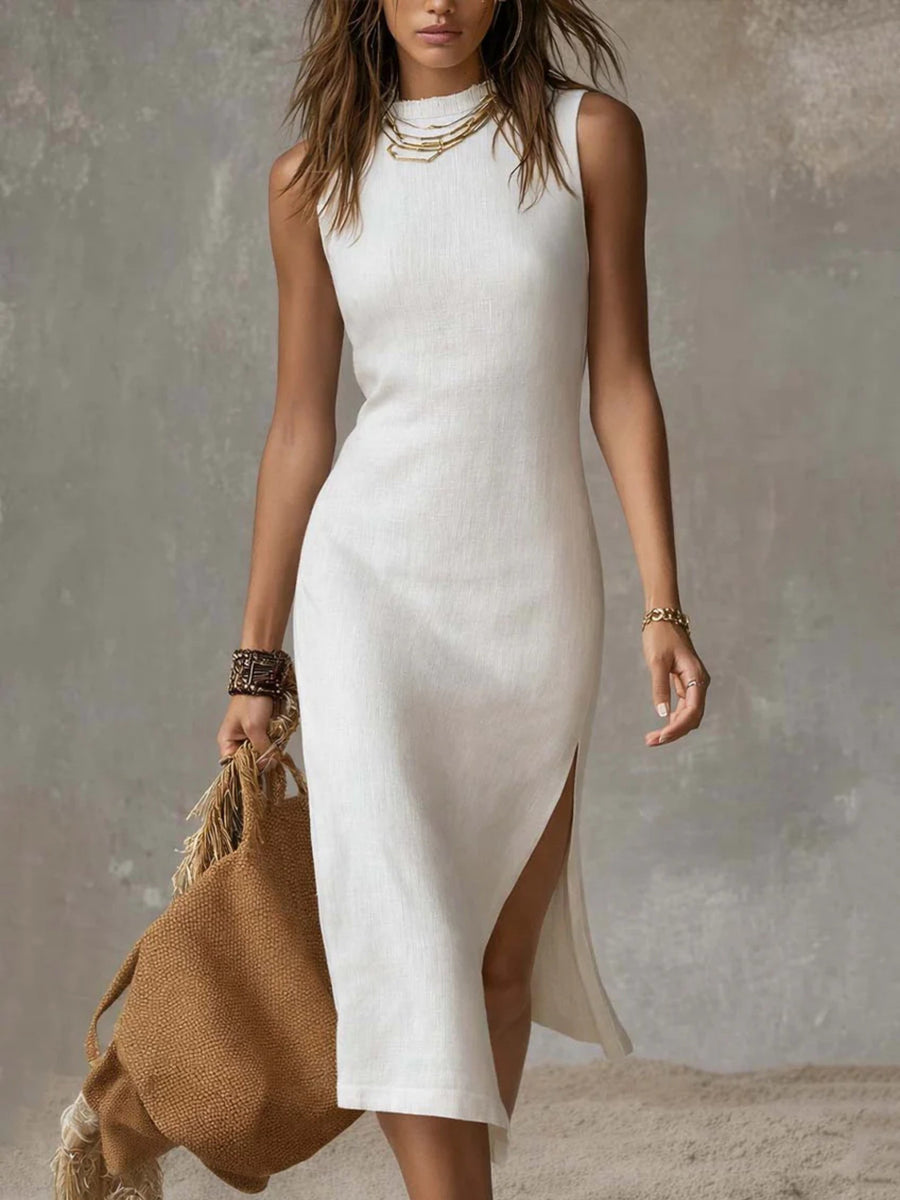 Woman wearing a white sleeveless dress with a slit, holding a brown bag against a neutral background.