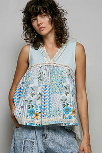 Woman wearing a sleeveless, patchwork-style top with floral and geometric patterns on a plain background.