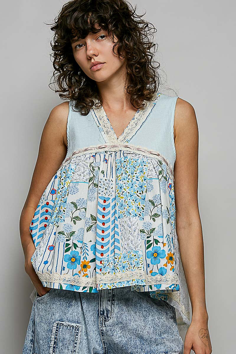 Woman wearing a sleeveless, patchwork-style top with floral and geometric patterns on a plain background.