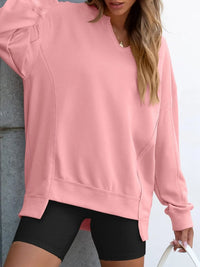 Person wearing a pink sweatshirt and black shorts against a light background