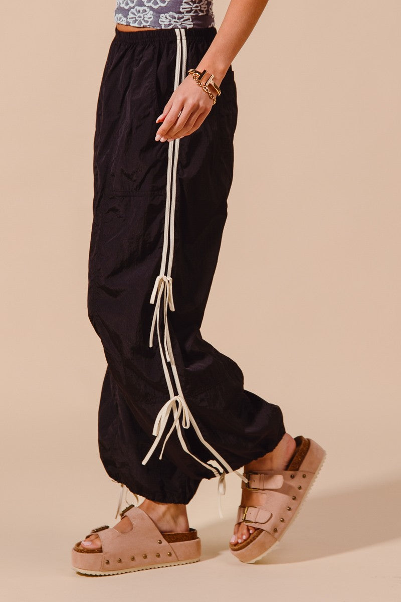 Person wearing black pants with white drawstrings on a beige background