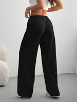Person wearing black wide-leg pants against a white background