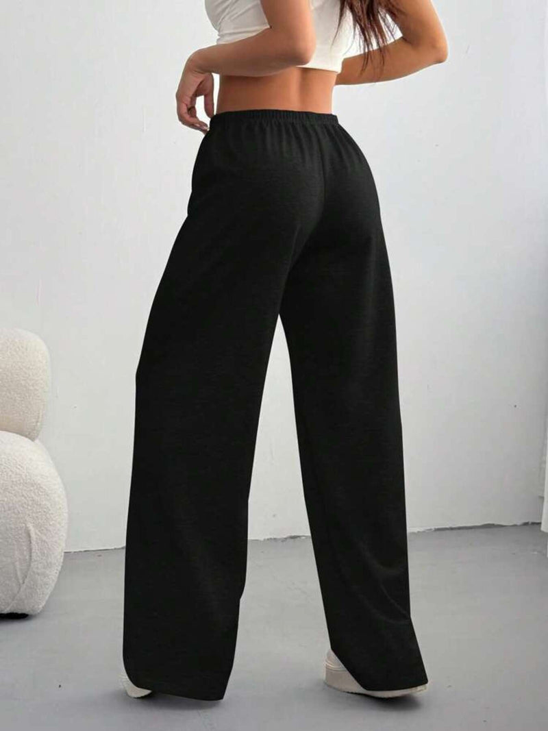 Person wearing black wide-leg pants against a white background
