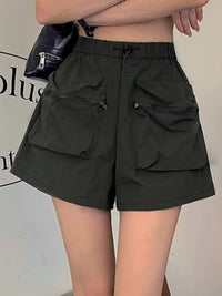 Person wearing dark green shorts with multiple pockets against a neutral background