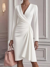 White dress with long sleeves held by a person in a neutral setting