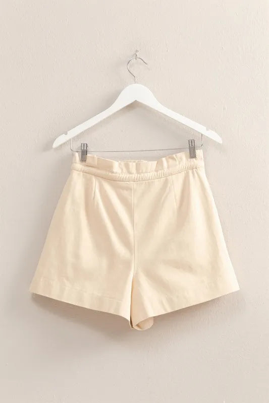 Beige shorts on a hanger against a beige background