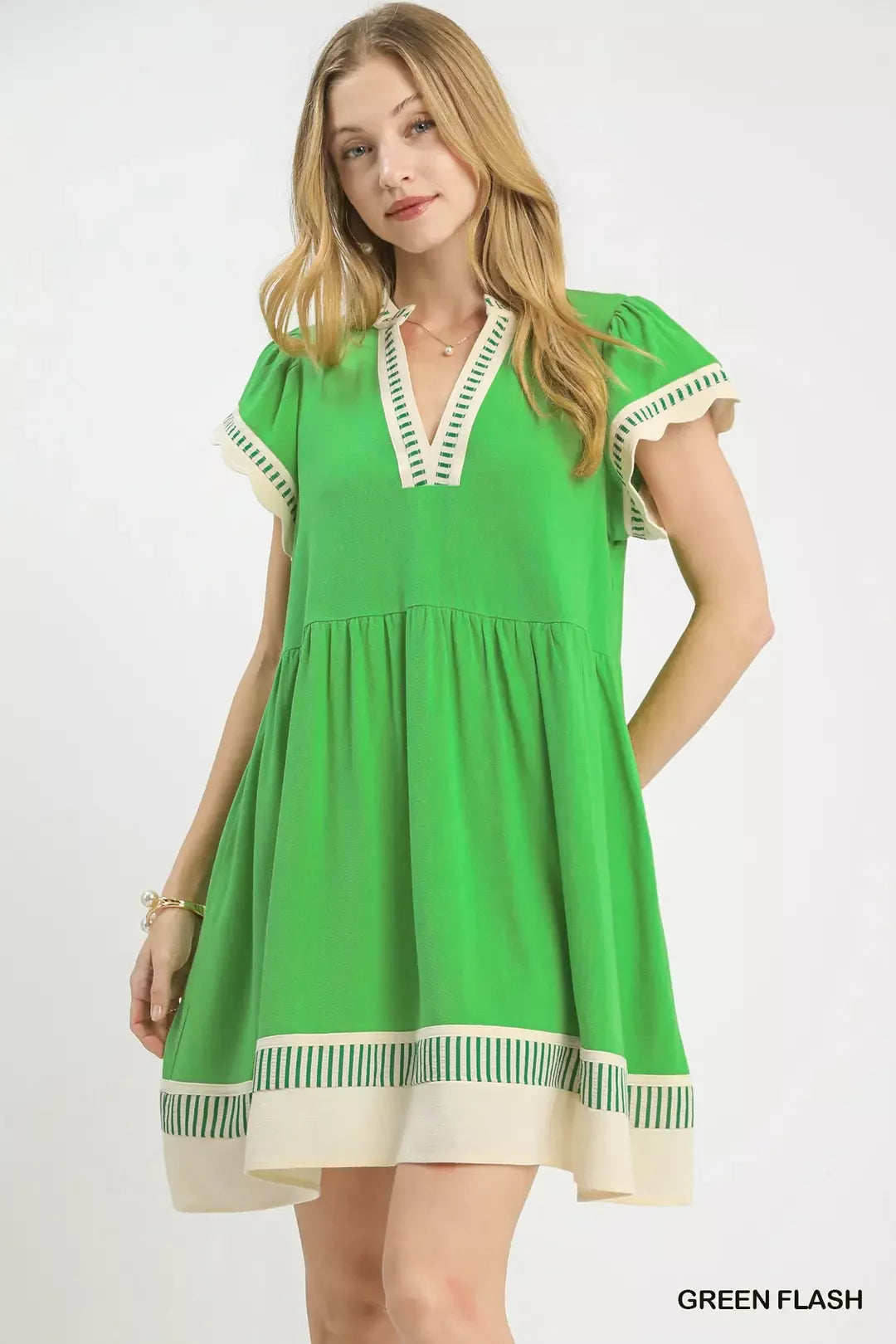 Woman wearing a green dress with white accents on a white background