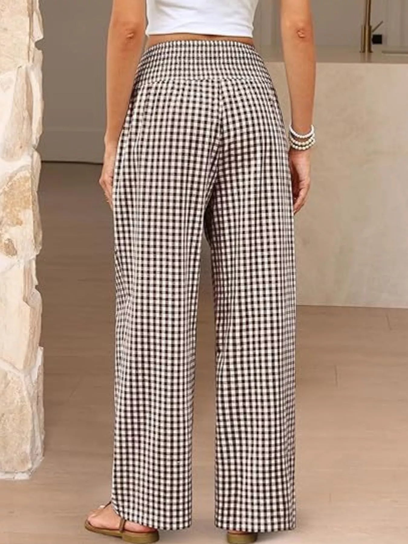 Person wearing black and white checkered pants in a neutral setting
