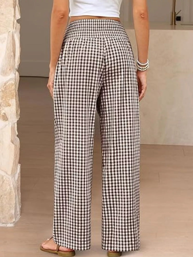 Person wearing black and white checkered pants in a neutral setting