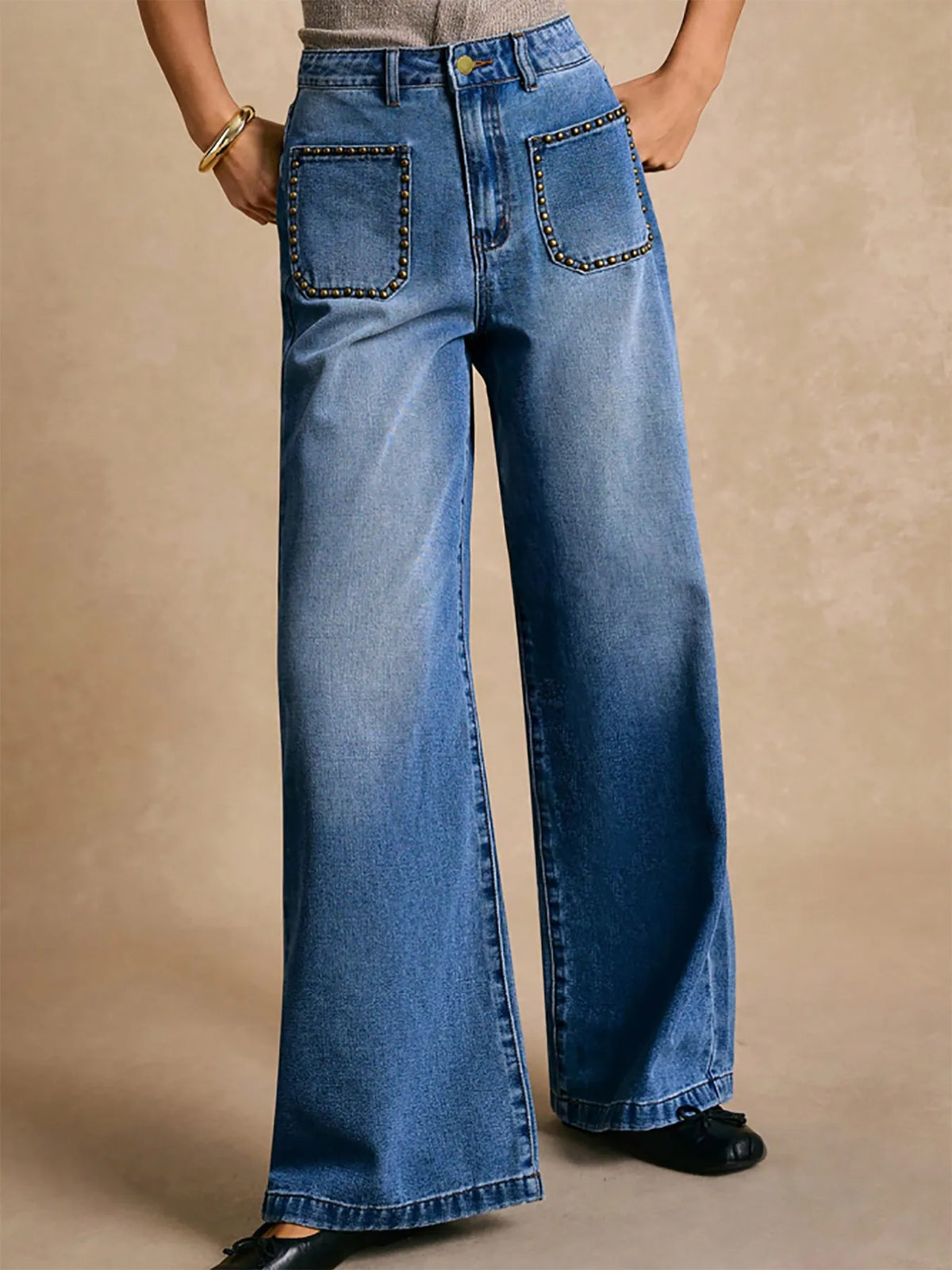 Blue wide-leg jeans with decorative stitching on a beige background