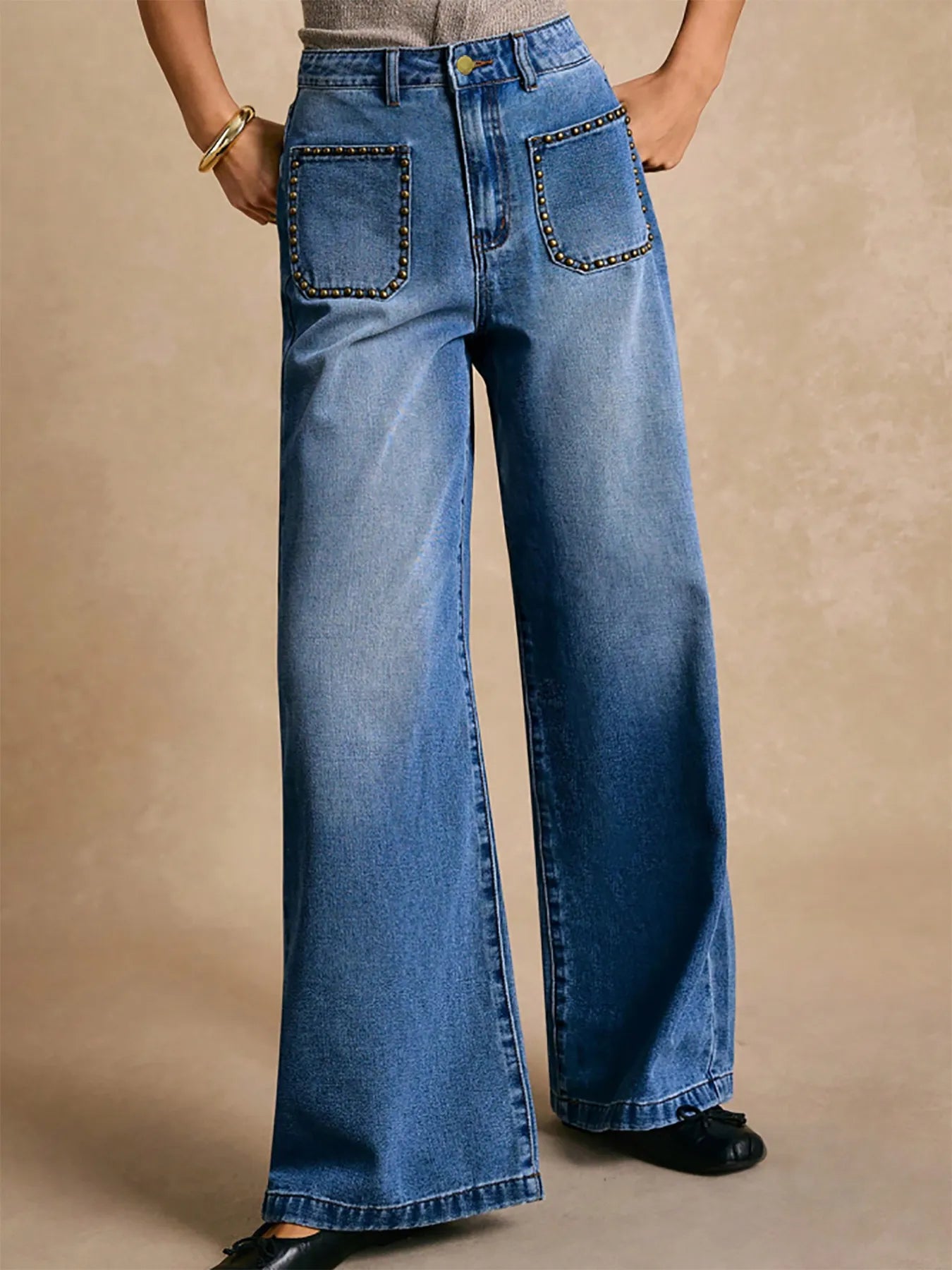 Blue wide-leg jeans with decorative stitching on a beige background