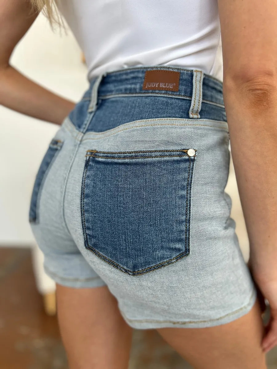 Person wearing light blue denim shorts with a white background