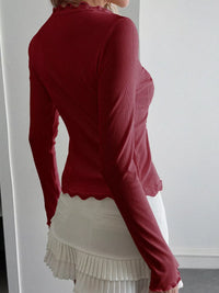 Red long-sleeve top worn by a person against a white background