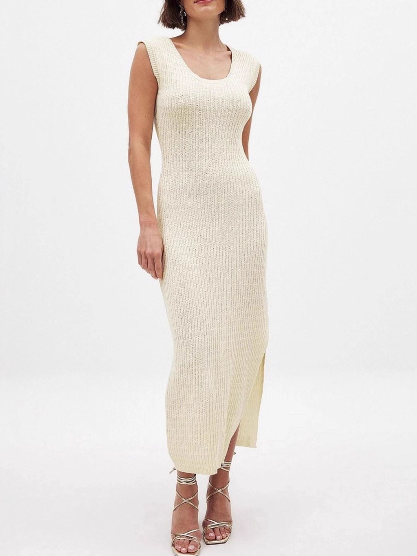 Woman wearing a cream ribbed dress on a white background