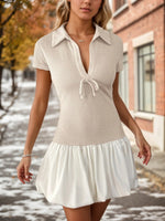 Woman wearing a white dress with a textured top and ruffled skirt on a snowy street.