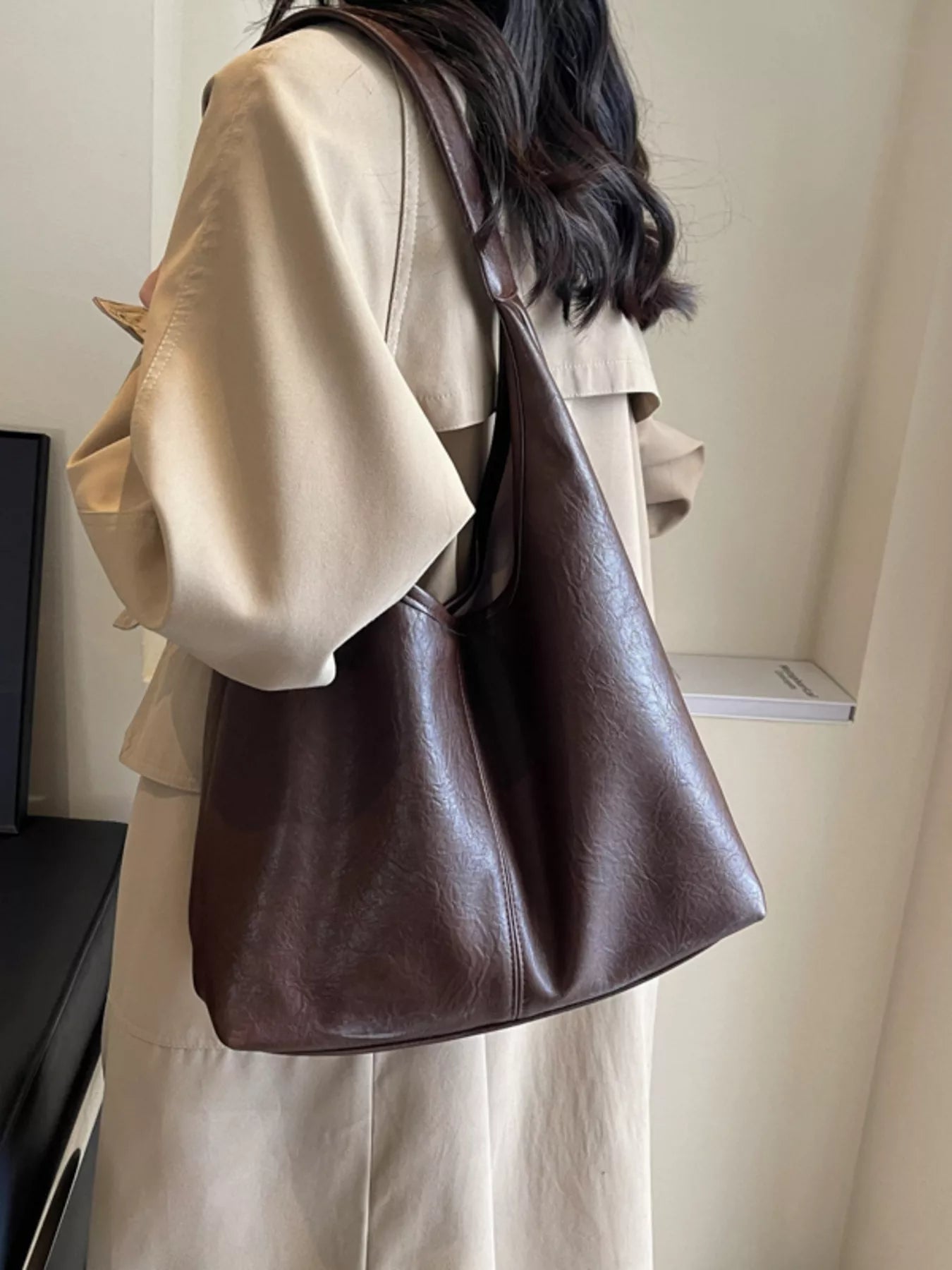 Person wearing a brown leather handbag indoors