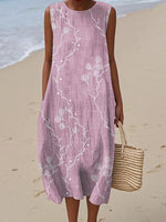 Woman wearing a pink sleeveless dress with white floral patterns on a beach.