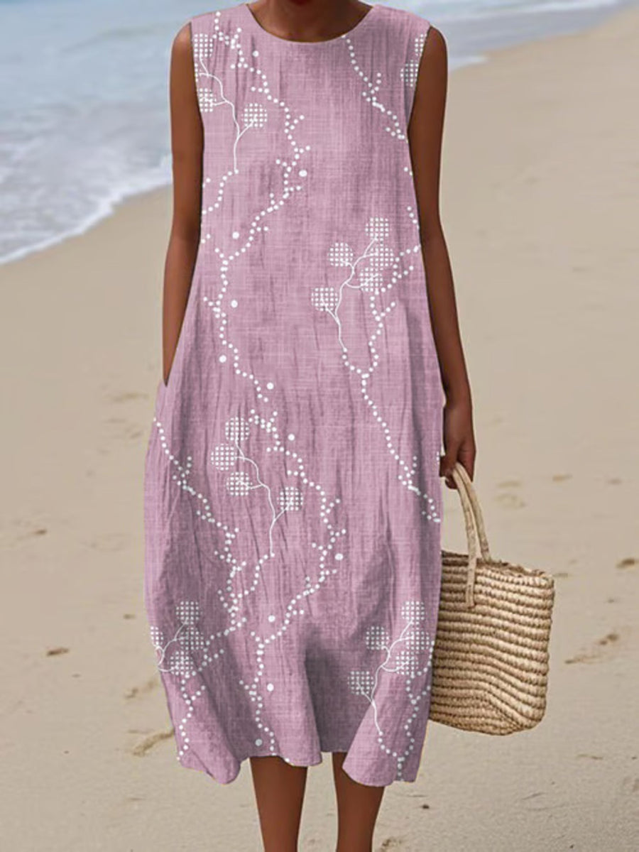 Woman wearing a pink sleeveless dress with white floral patterns on a beach.