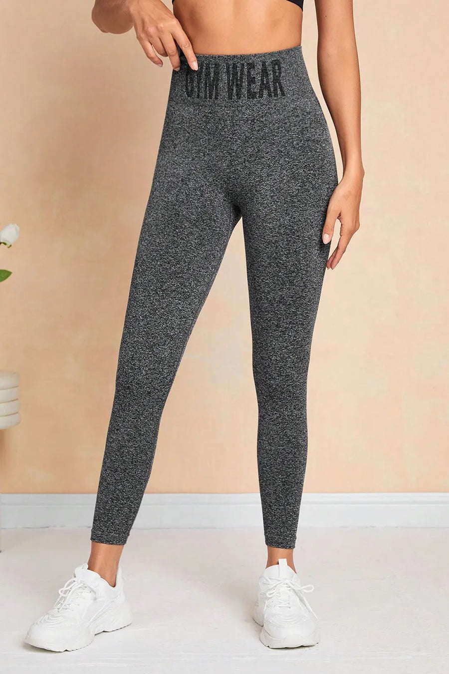 Person wearing gray leggings with 'Gym Wear' text on a beige background