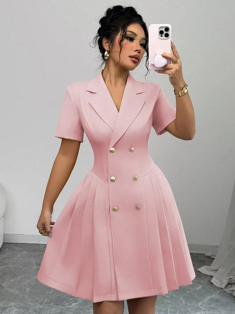 Woman wearing a pink dress with gold buttons, taking a mirror selfie.