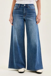 Person wearing blue wide-leg jeans on a plain background