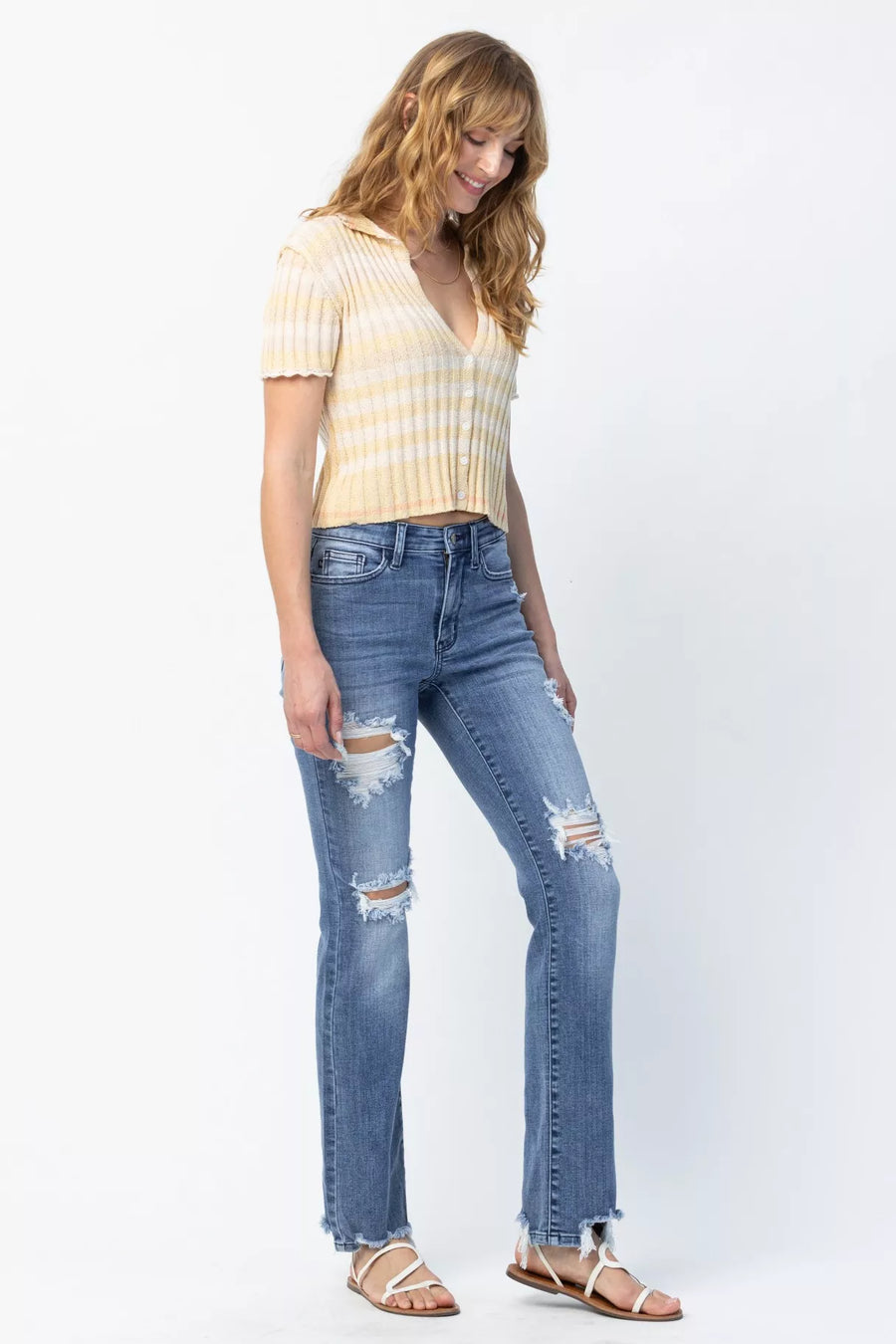 Woman wearing a yellow striped shirt and blue jeans on a white background