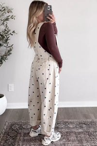 Woman taking a mirror selfie wearing a polka dot jumpsuit indoors.