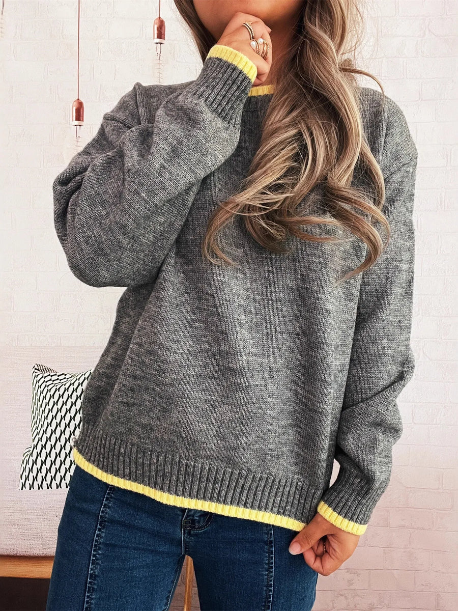 Person wearing a gray sweater with yellow trim in a casual setting