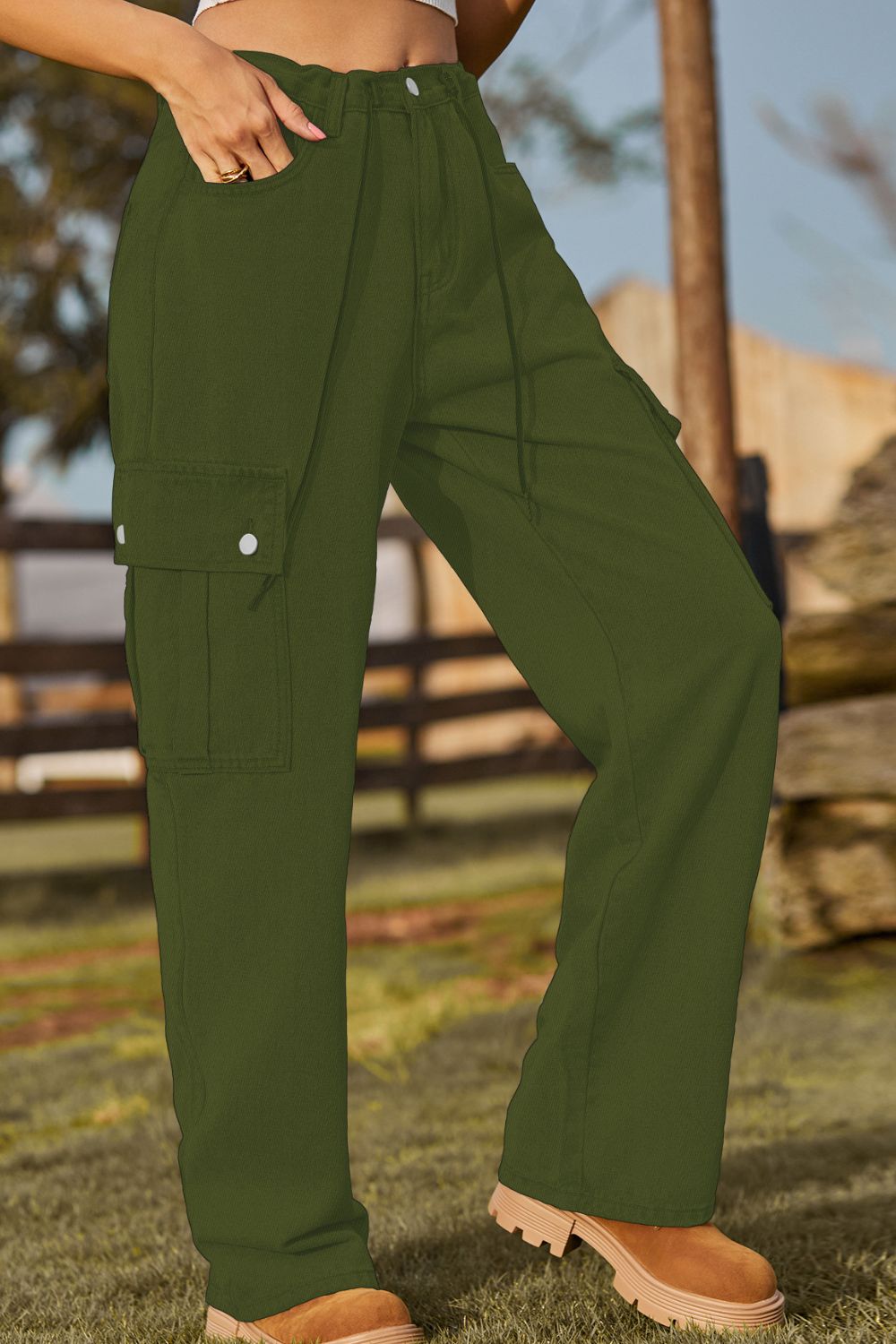 Person wearing green cargo pants with a blurred outdoor background