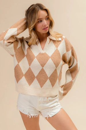 Woman wearing a beige and white argyle sweater with white shorts on a beige background