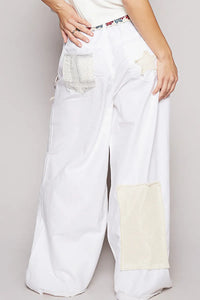 White wide-leg jeans with patchwork design on a plain background