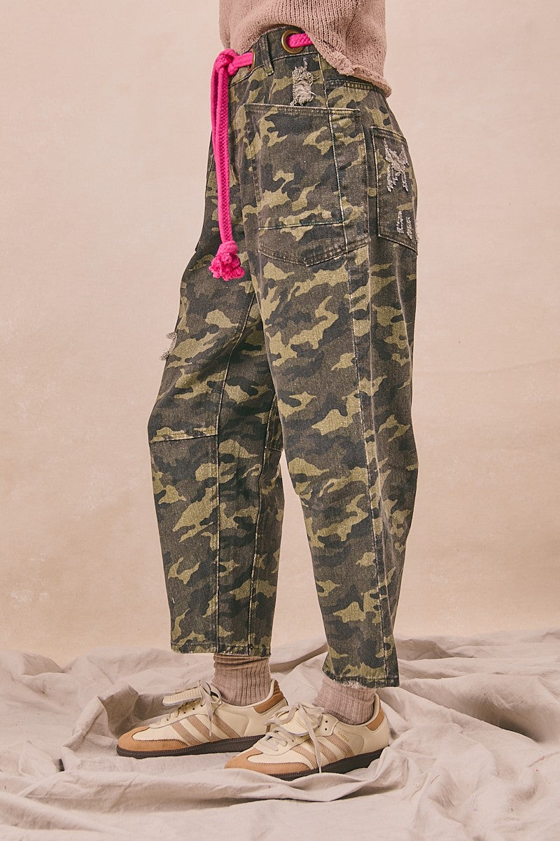 Camouflage pants with pink drawstring worn by a person on a neutral background