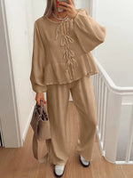 Person wearing a beige outfit with a matching handbag indoors.