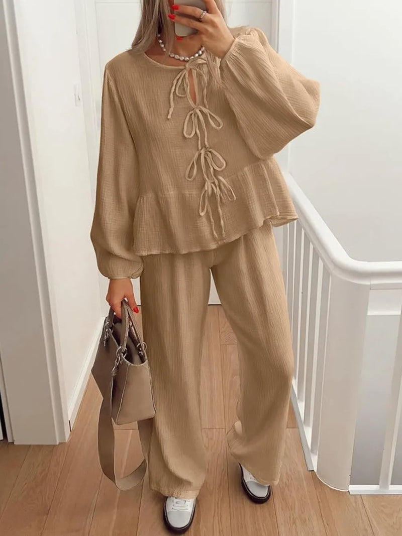Person wearing a beige outfit with a matching handbag indoors.
