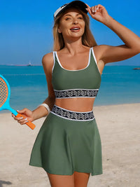 Woman in green sports outfit holding a badminton racket on a beach