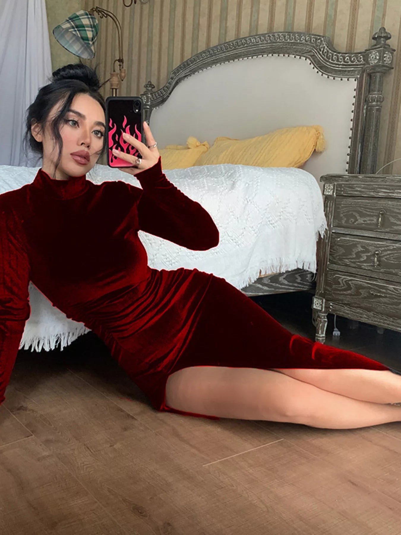 Woman in a red dress taking a mirror selfie in a bedroom.