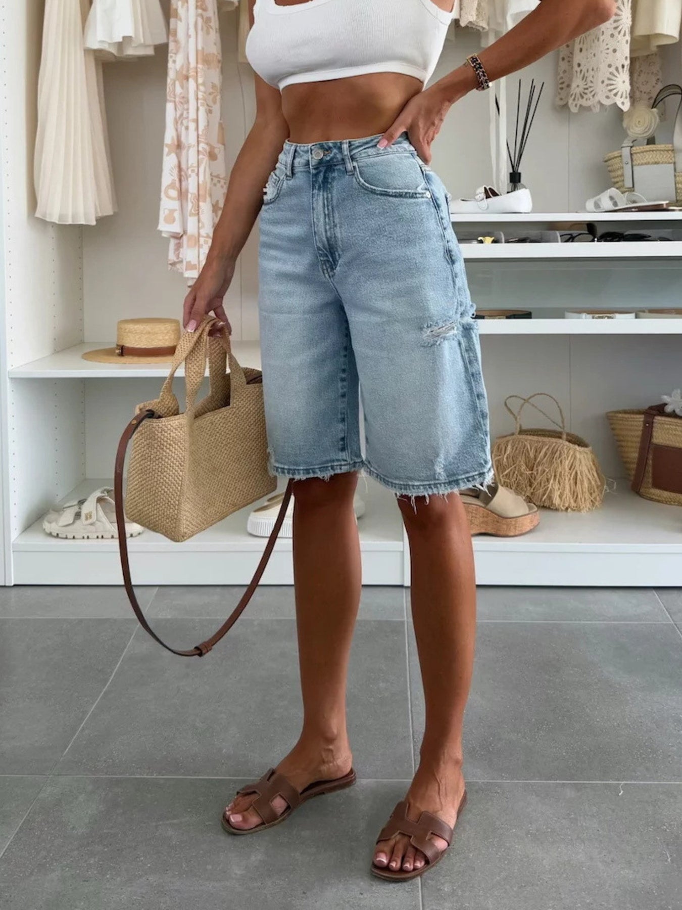 Person wearing denim shorts holding a straw bag in a store setting
