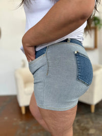 Person wearing light blue denim shorts with a blurred indoor background