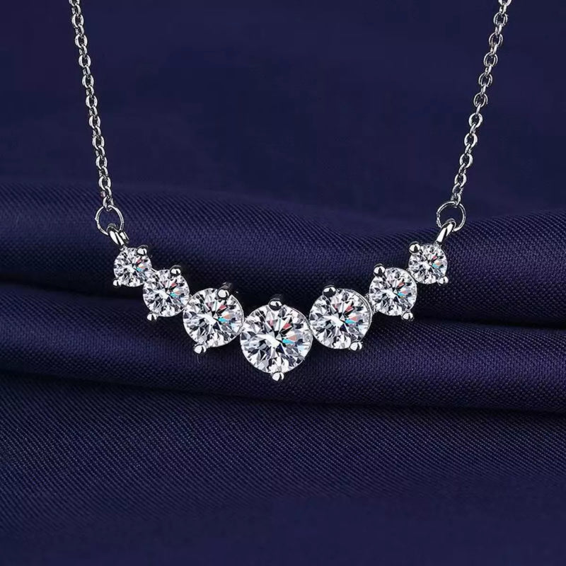 Silver necklace with clear gemstones on a dark blue fabric background