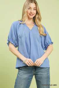 Woman wearing a blue blouse and jeans on a light green background