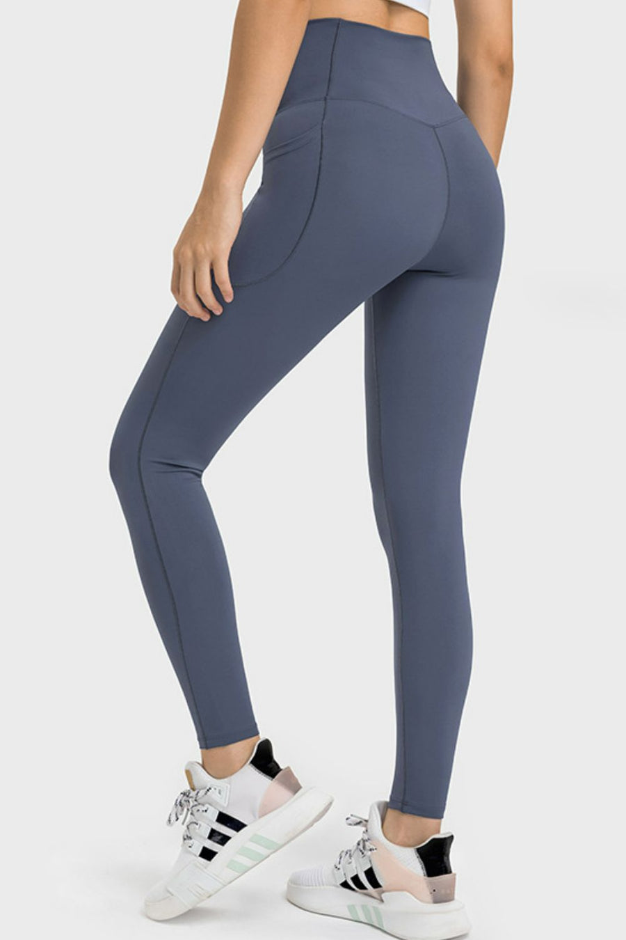 Person wearing blue leggings with white sneakers on a white background