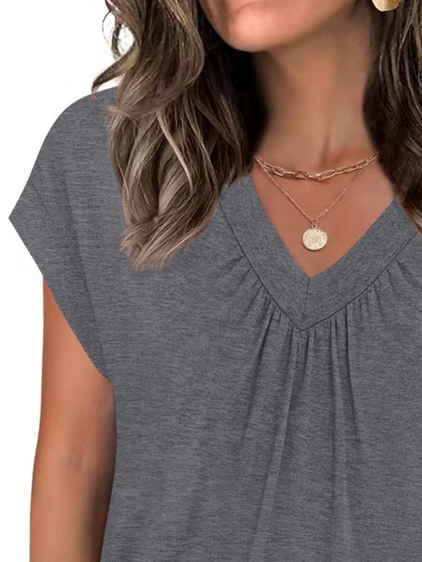 Gray short-sleeve top worn by a person, with a focus on the neckline and shoulders.