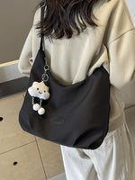 Person holding a black bag with a cloud-shaped keychain