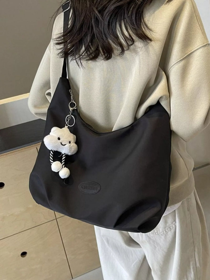 Person holding a black bag with a cloud-shaped keychain