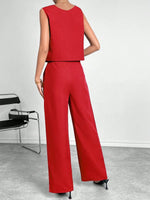 Person wearing a red outfit with wide-leg pants in a minimalistic setting.