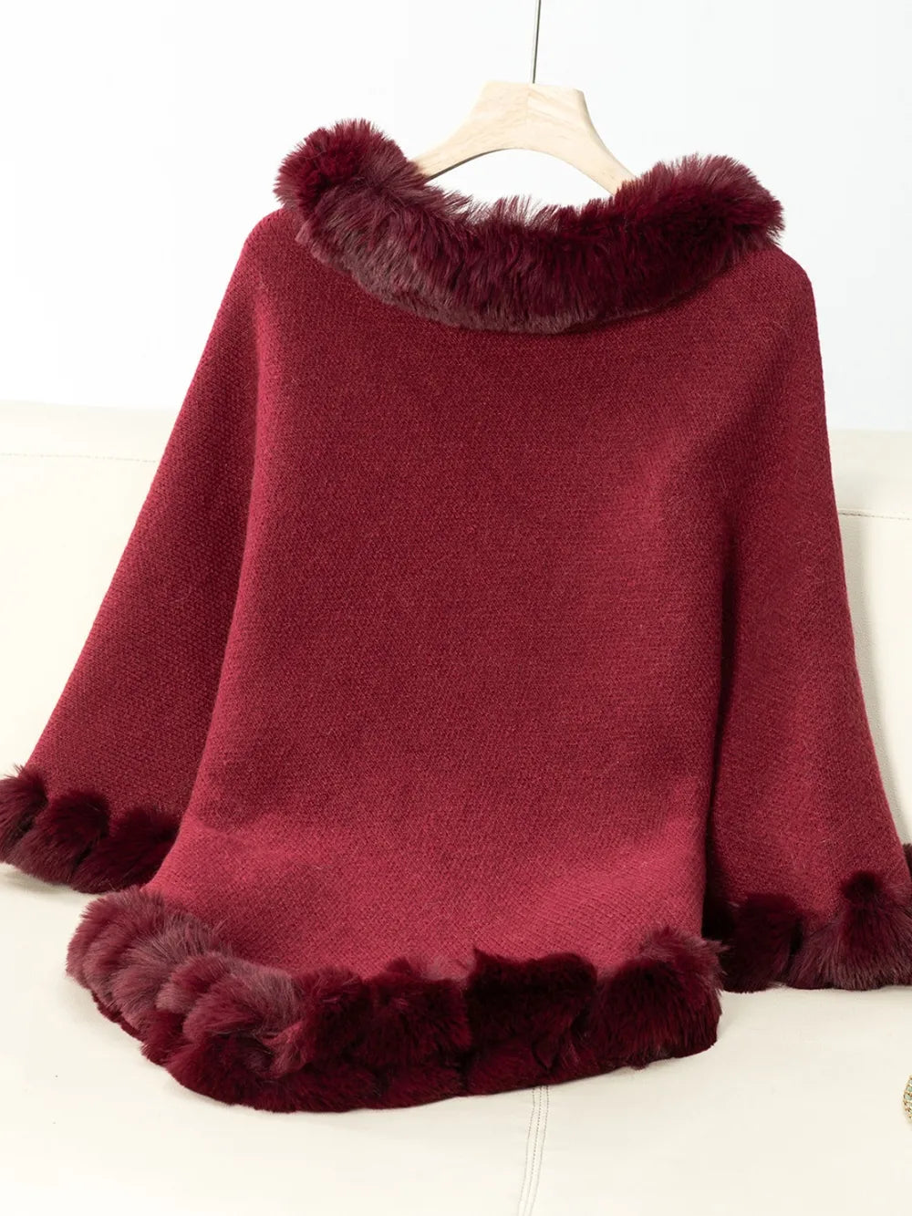 Red poncho with fur trim on a white background