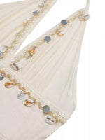 Close-up of a decorative fabric edge with beads and sequins on a white background