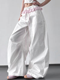 White wide-leg pants with pink waistband and trim on a plain background