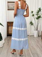 Woman wearing a blue and white striped dress with floral details in a room.